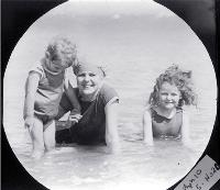 A mother with her two children paddling in the surf, possibly at a Wellington beach [ca. 1900]