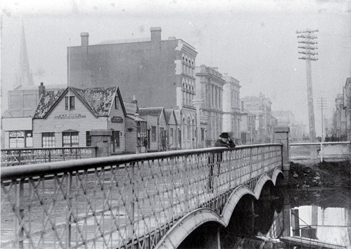 A boy leans on the Hereford Street bridge, Christchurch, looking to the east 