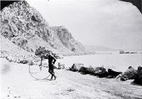 Cyclist beside penny-farthing bicycle near Shag Rock on the Sumner road, Christchurch