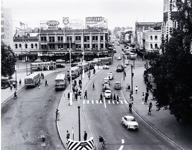 Cars and buses in Cathedral Square : view looking up Colombo Street, with the Colonial Mutual Life building behind the Cathedral 