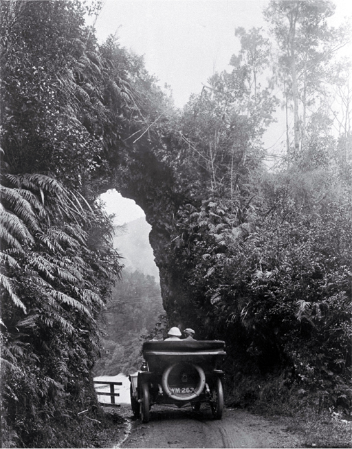 A Model T Ford (Tin Lizzie) travelling under a rock arch in the Buller Gorge, Westland 