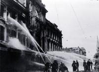 Firemen dampening down the main entrance of Ballantyne's building, Christchurch