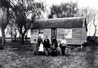 The family of Arthur John Inwood (1850-1932) and his wife Angelina (1860?-1919) pictured outside their dwelling 