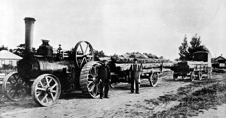 Traction engine and trucks loaded with piles leaving Leeston Station.