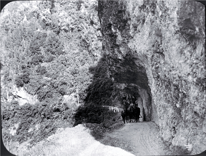 A coach travels under Hawk's Crag in the Buller Gorge, West Coast 