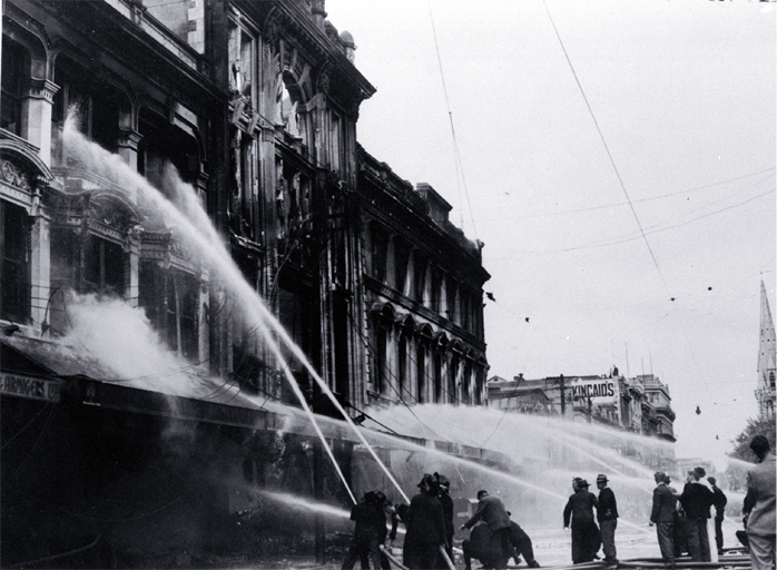 Firemen dampening down the main entrance of Ballantyne's building, Christchurch 