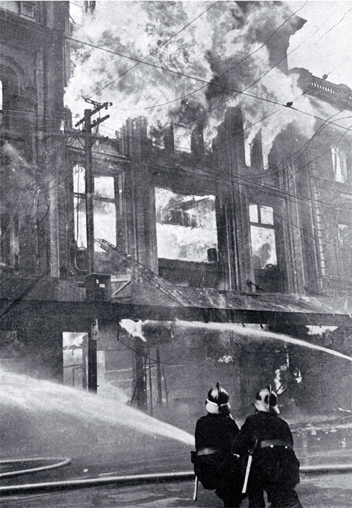 Firemen battling the blaze : directing jets on the furniture department.