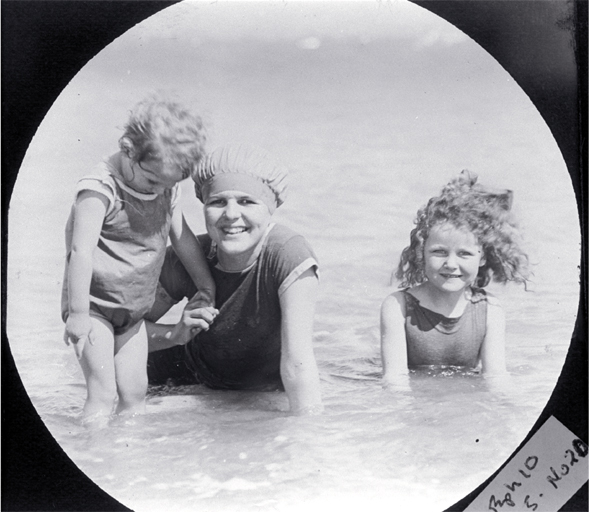 A mother with her two children paddling in the surf, possibly at a Wellington beach A mother with her two children paddling in the surf, possibly at a Wellington beach