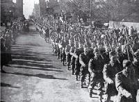 Second echelon of New Zealand Expeditionary Forces march west along Cashel Street, under the Bridge of Remembrance 
