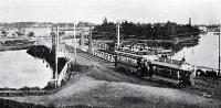 An electric tram crosses the Ferry Bridge over the Heathcote River on the road to Sumner, Christchurch 